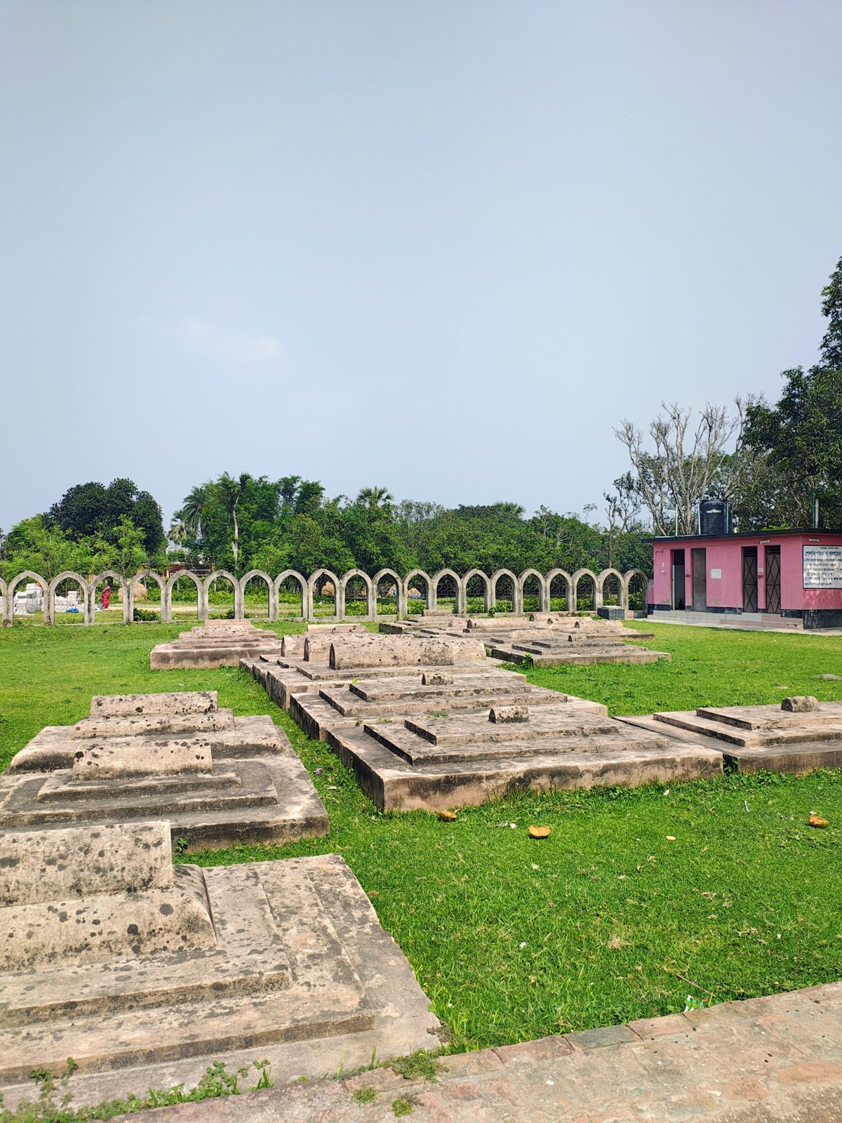 Rows of old stone graves and arched wall in the Sona Masjid heritage area