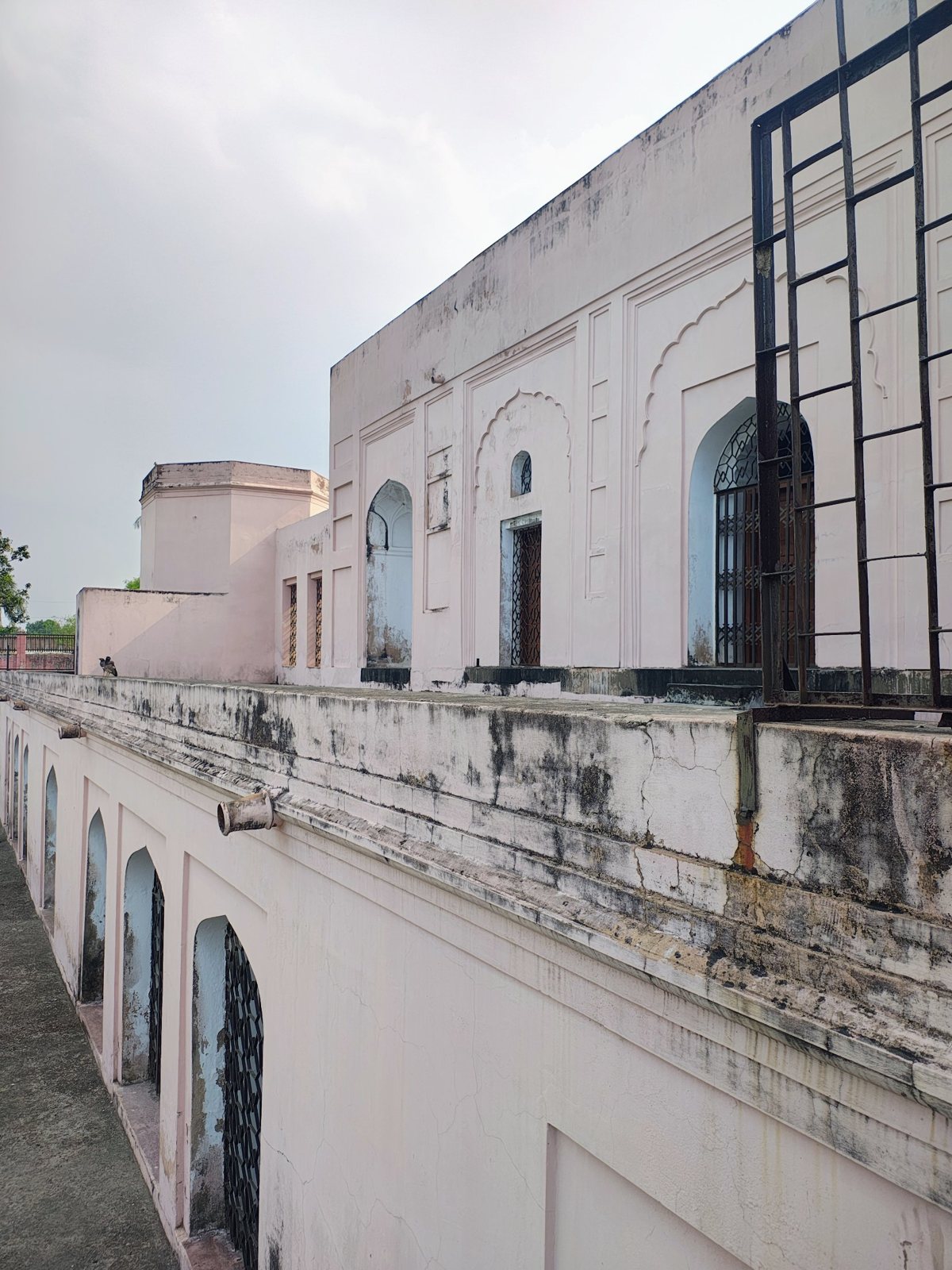 Pale pink heritage-style building with arched latticed windows and scalloped niches in Chapainawabganj