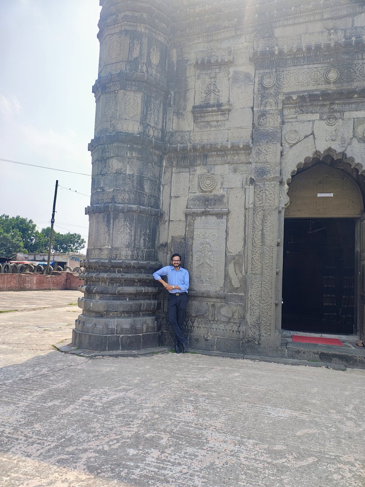 Sayedul Abrar beside the scalloped arched entrance and carved pillar of Sona Masjid